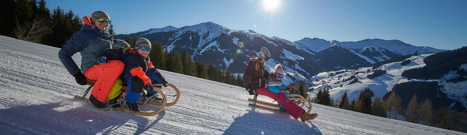 Eltern mit Kindern beim Rodeln | © saalbach.com, Daniel Roos